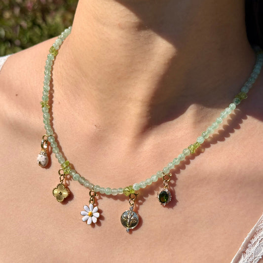 Necklace with green aventurine and peridot beads and charms worn by a person outdoors