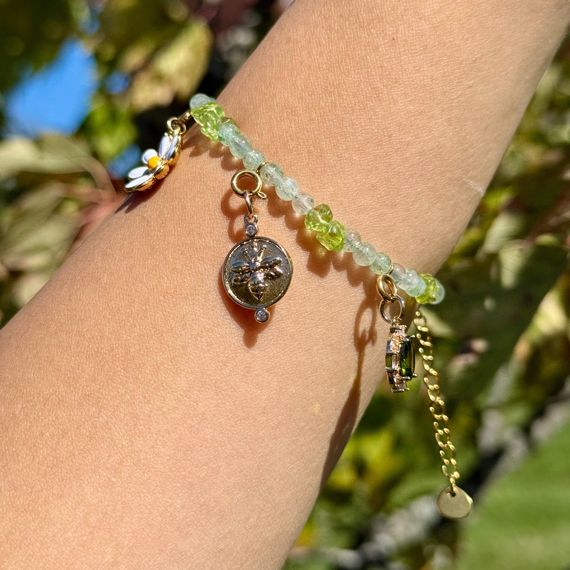 Bracelet with green beads and charms on a wrist against a natural background