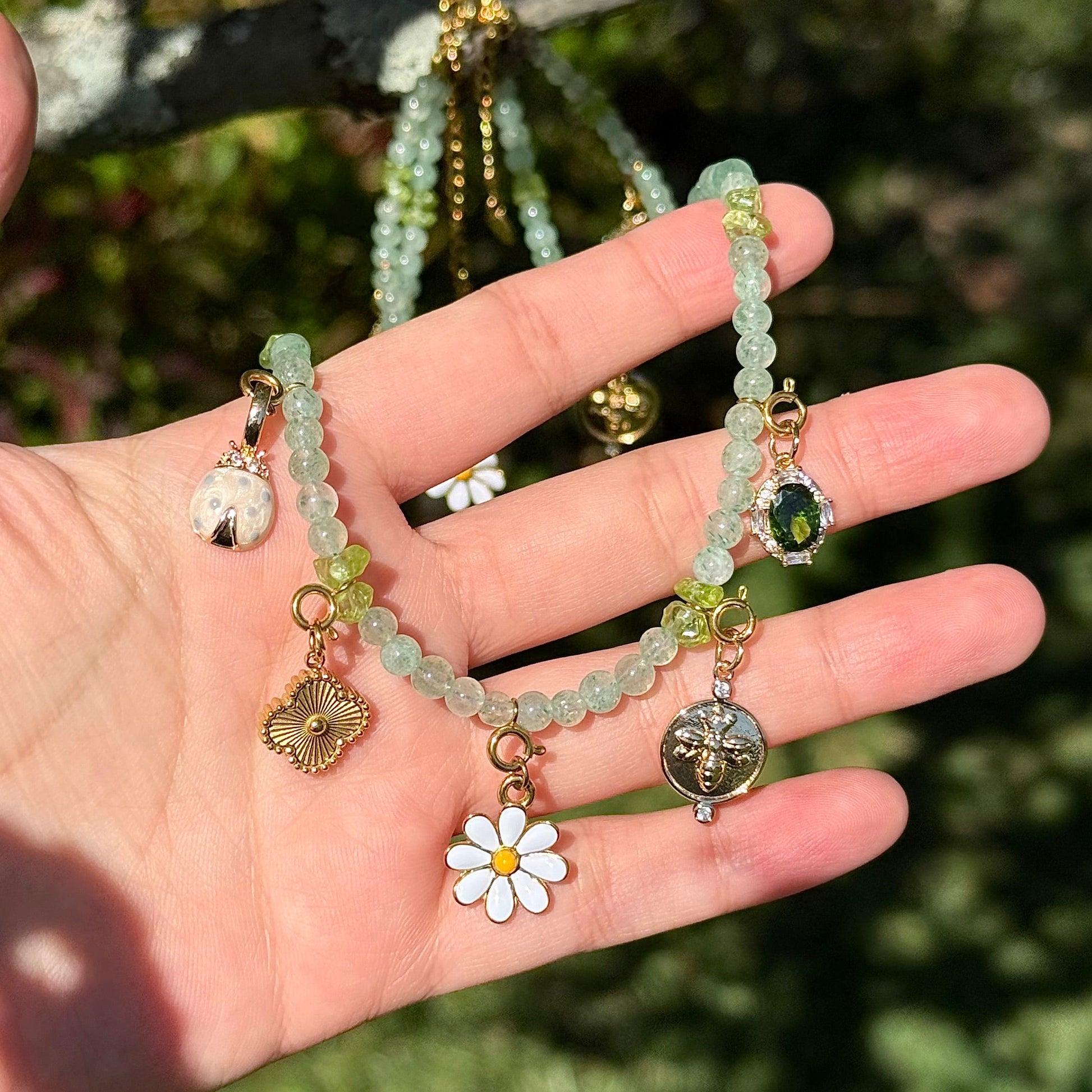 Hand holding a beaded bracelet with charms against a natural background