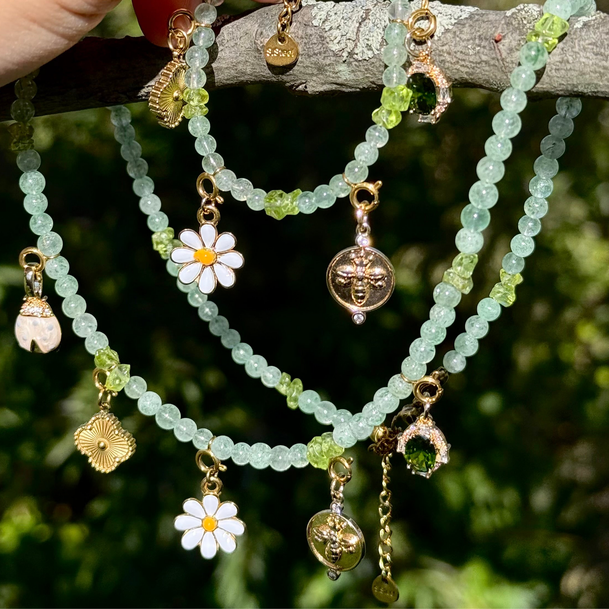 Crystal Statement Necklace set with floral and gold charm pendants on a branch with greenery in the background.