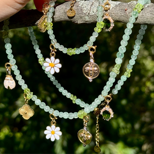 Crystal Statement Necklace set with floral and gold charm pendants on a branch with greenery in the background.