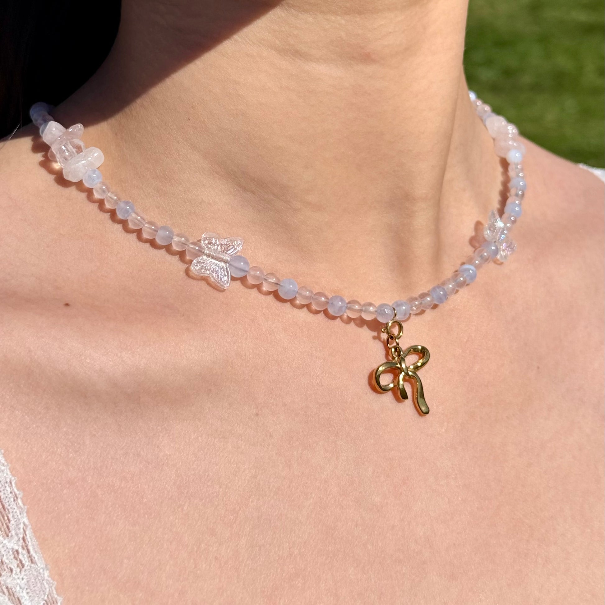 pink and blue crystal statement Necklace with butterfly charms and a gold bow pendant